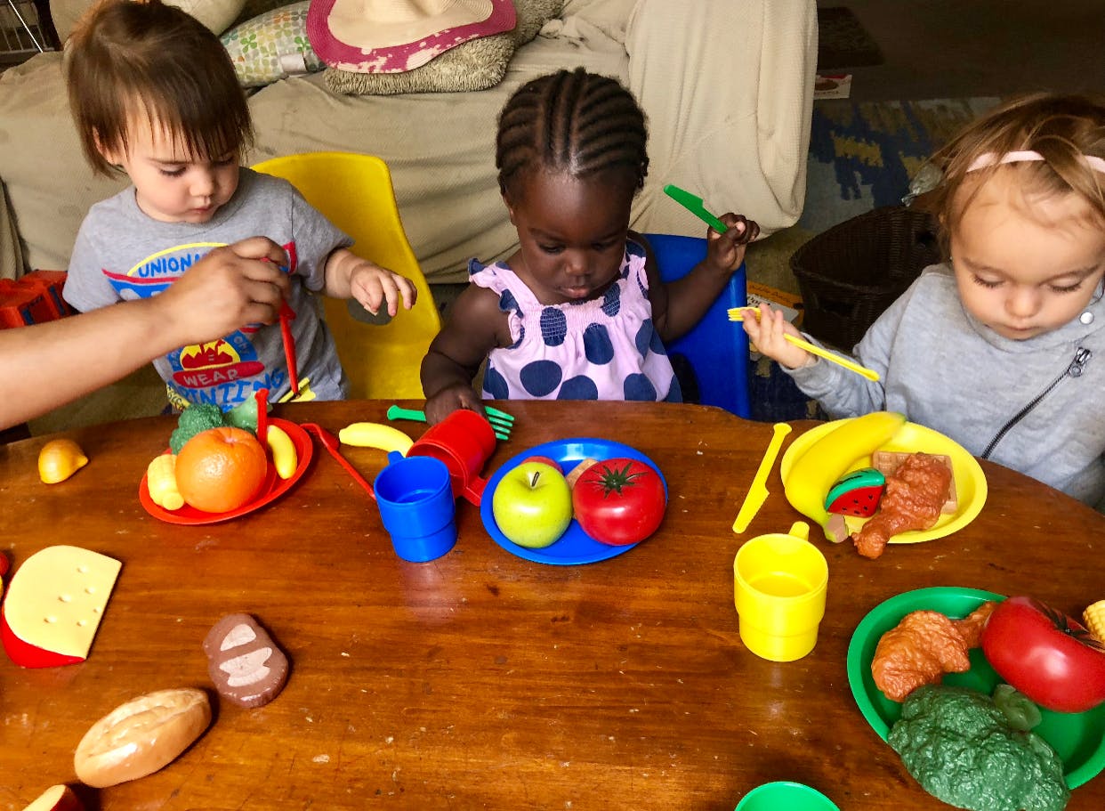 Three children playing with toy food at a table