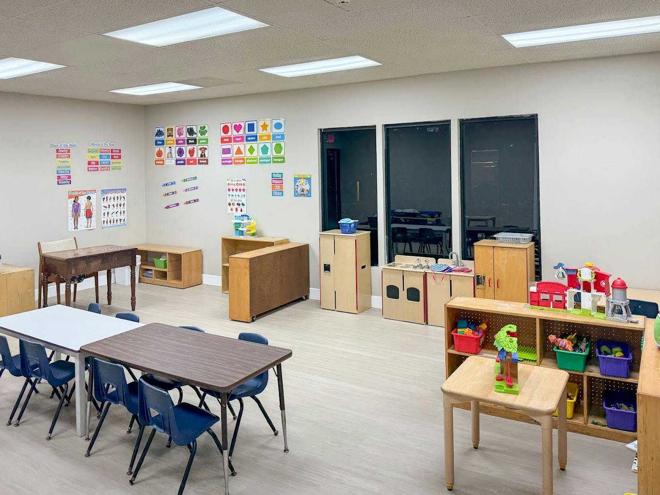 Empty preschool classroom with tables, chairs, and educational toys