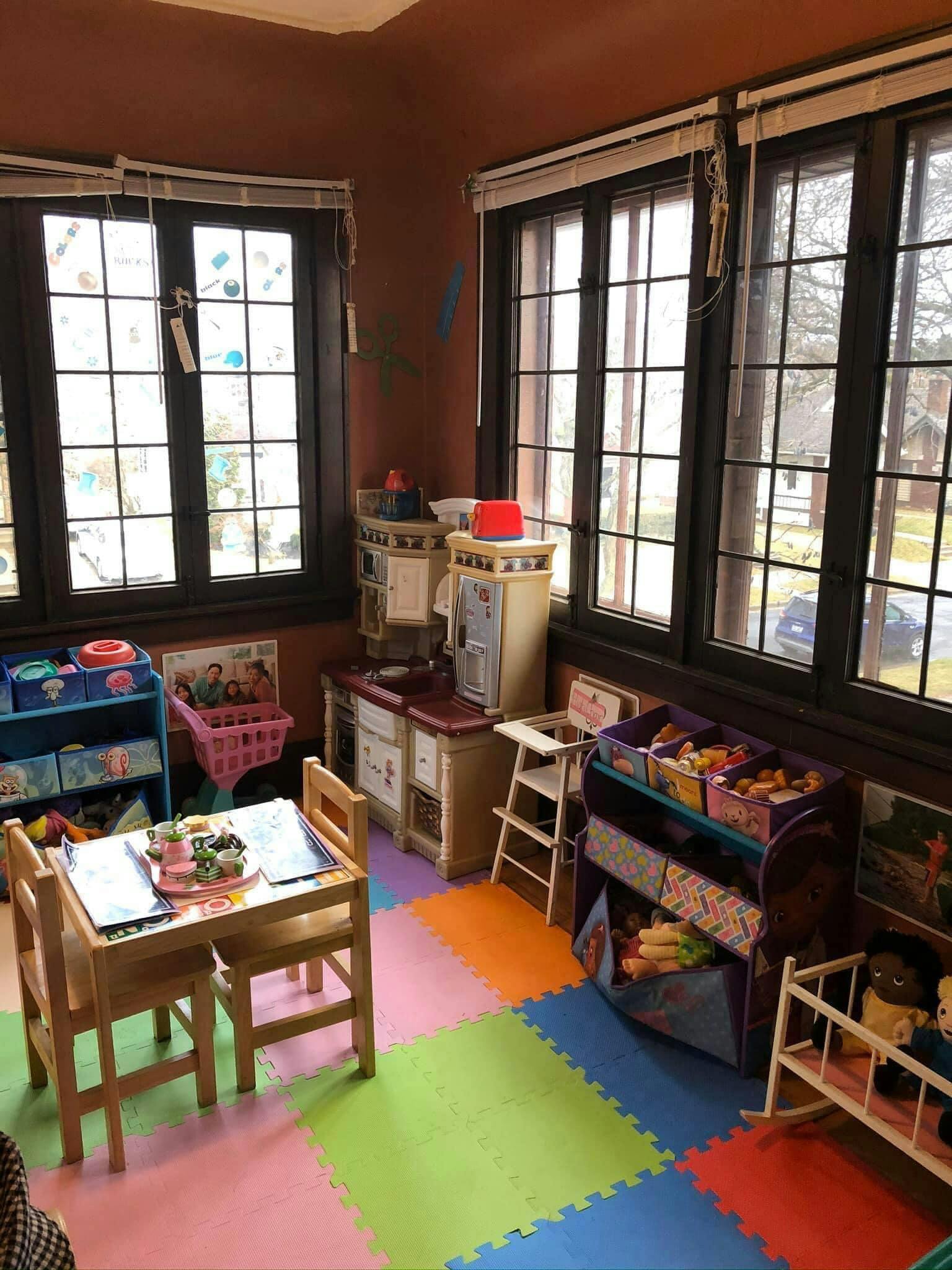 Playroom with child-sized table and chairs, play kitchen, and toy storage