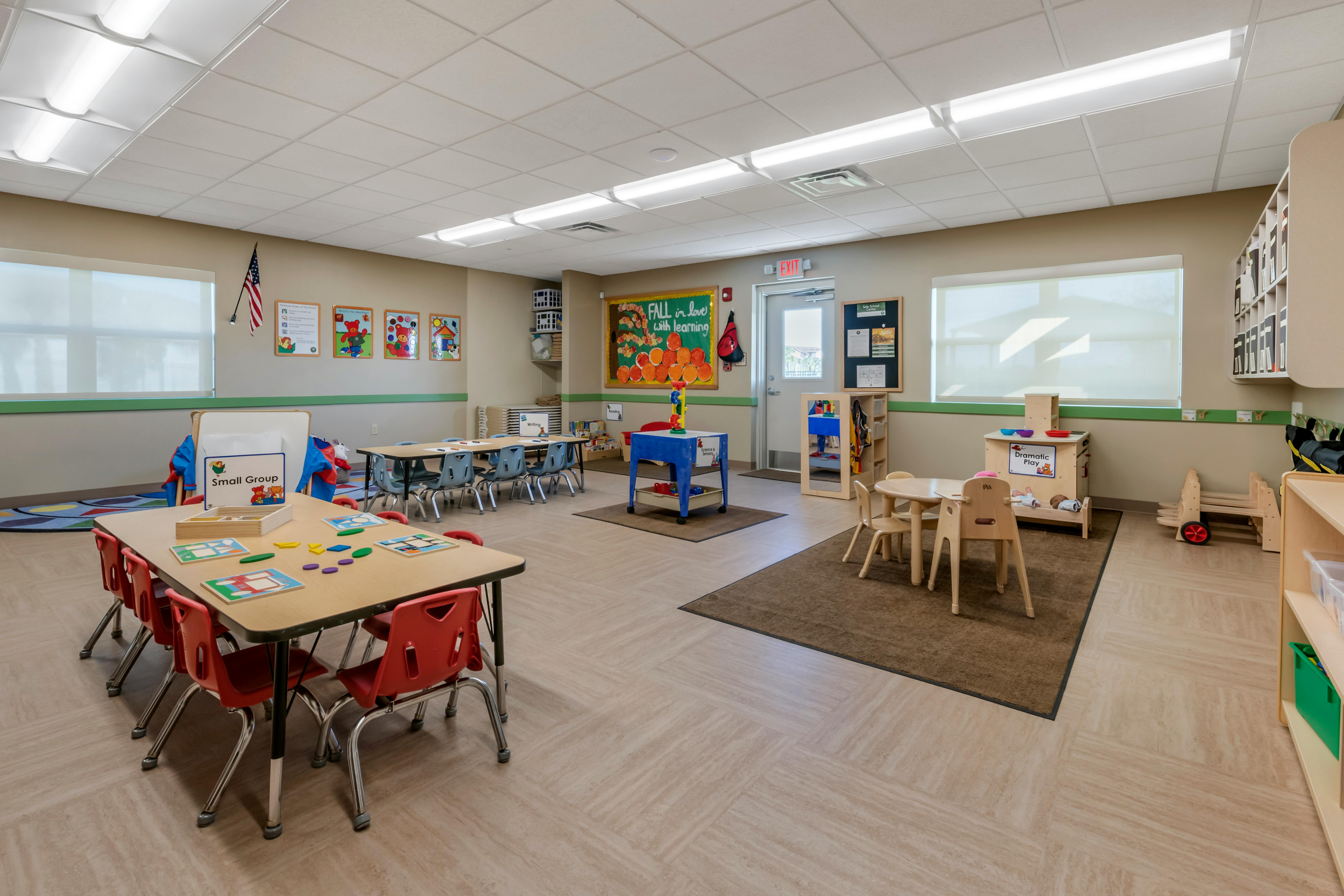Classroom with small tables and chairs, toys, and educational posters
