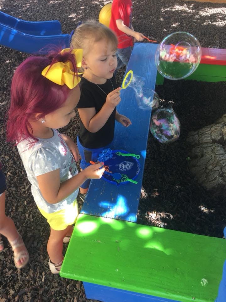 Two children playing with bubbles outdoors