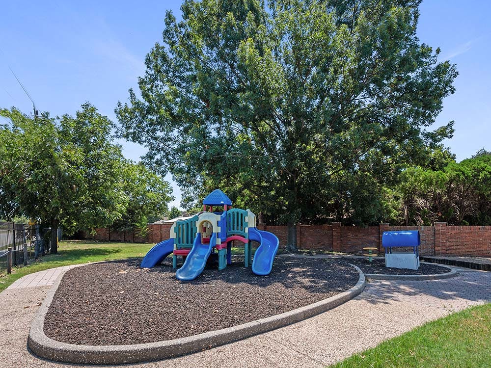 Colorful playground structure with slides on a wood chip base