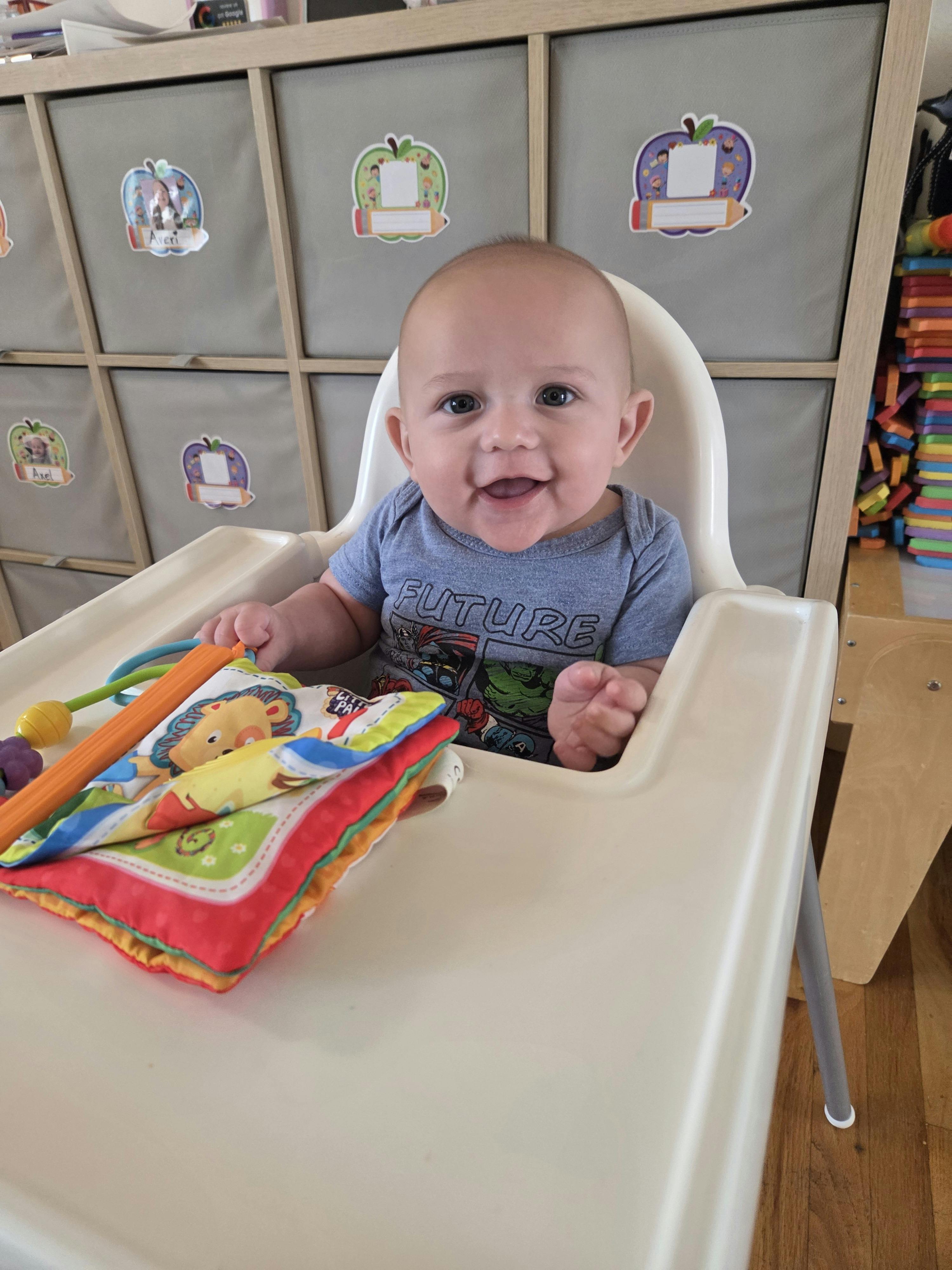 A baby sitting in a high chair with a soft book