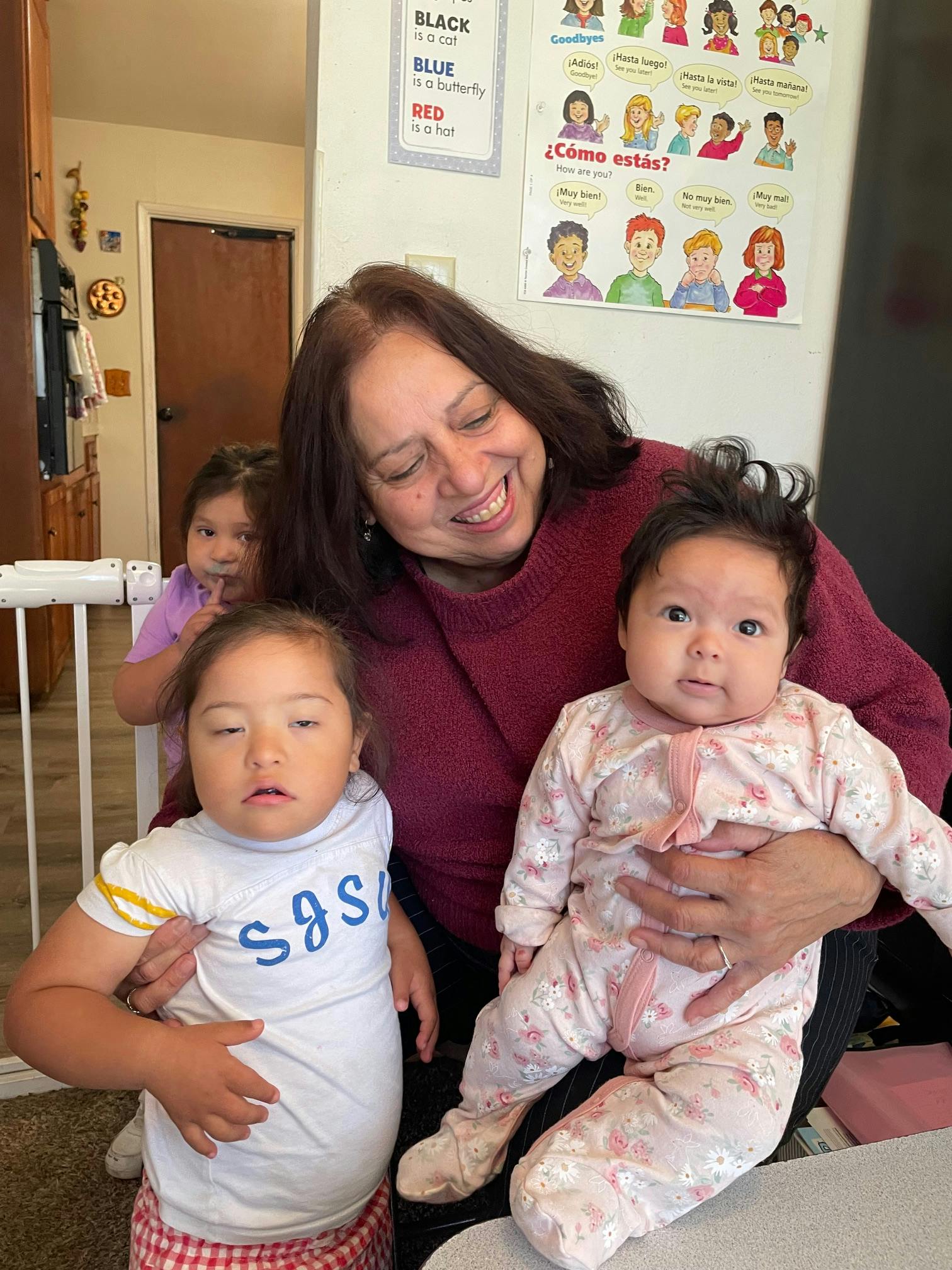 Person holding two children, with another child in the background