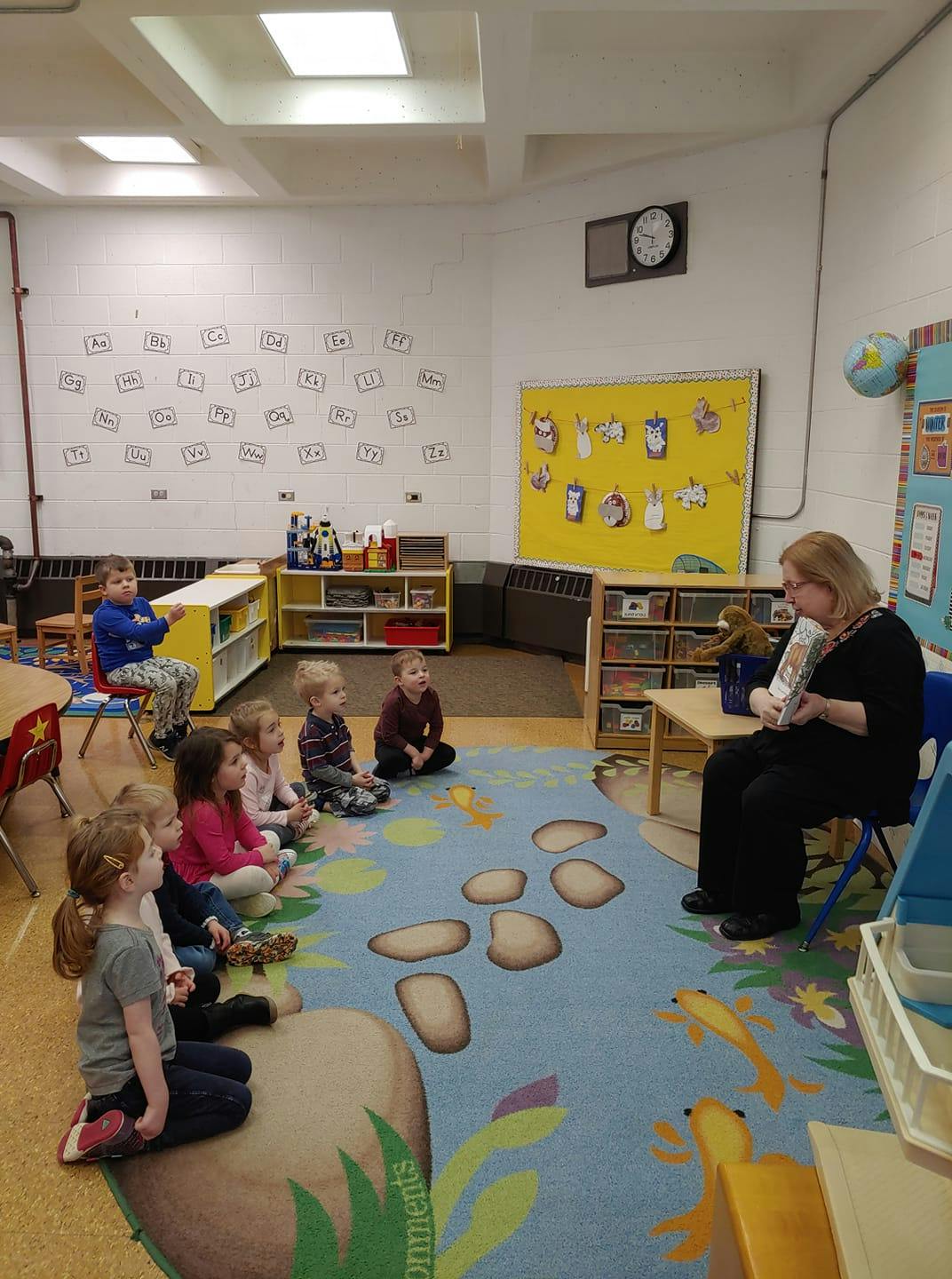 Adult reading to children sitting on a rug in a classroom