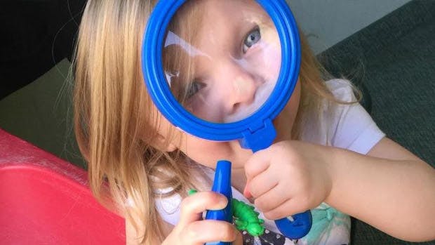 Child looking through a magnifying glass