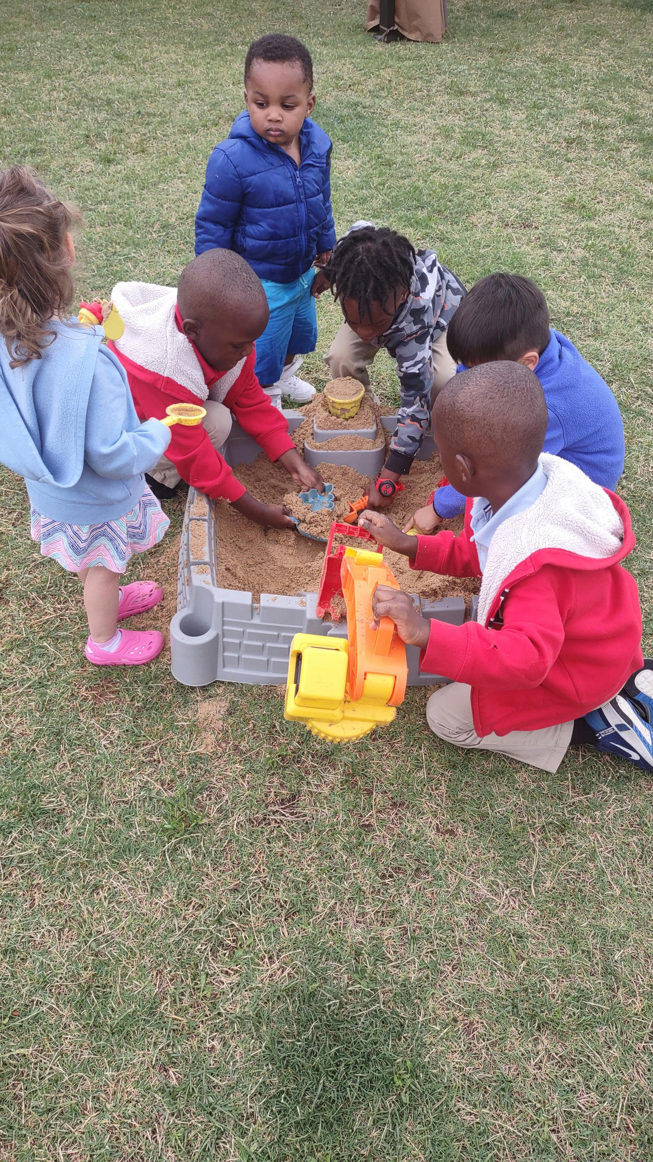 Children playing in a sandbox with toys