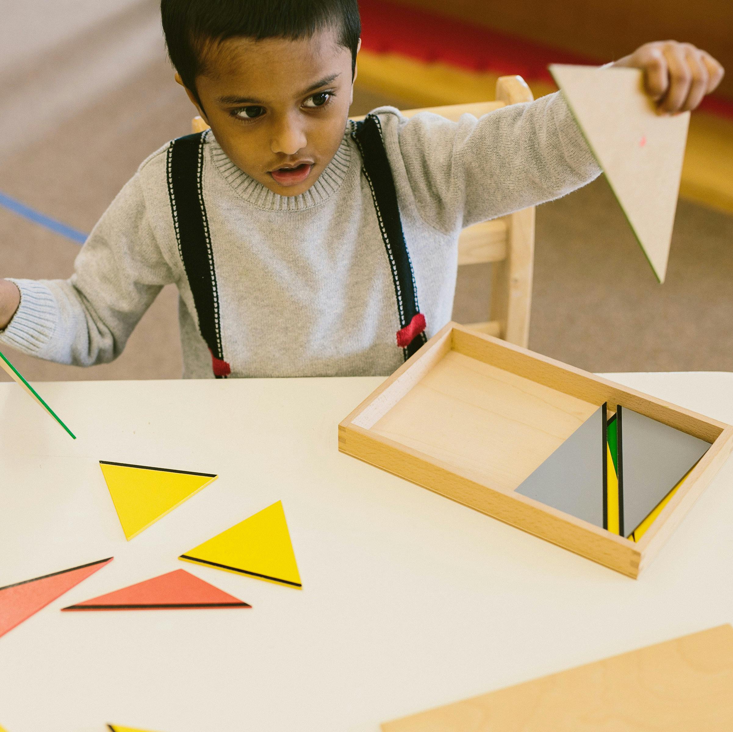 Child playing with triangle shapes on a table