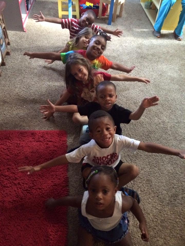 Children sitting in a line with arms outstretched