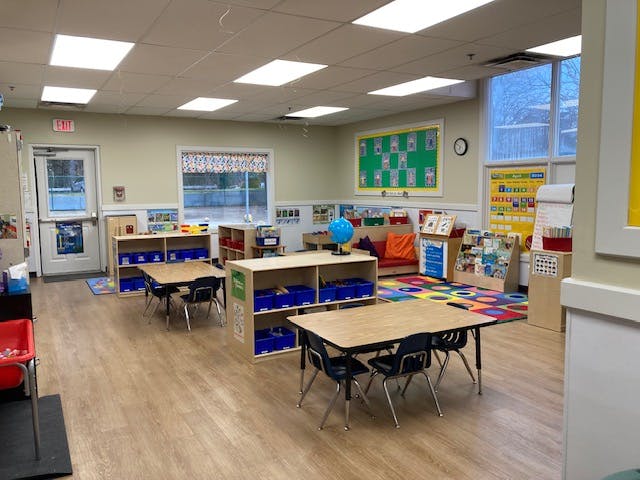 An empty early childhood classroom with small tables and chairs