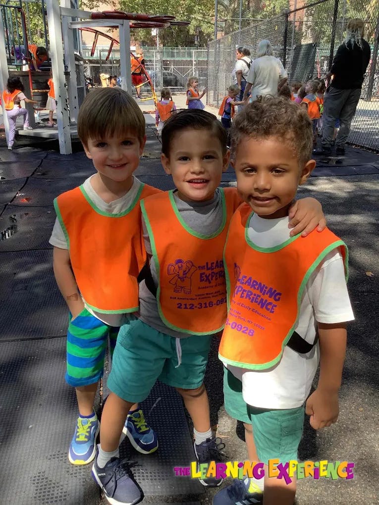 Three children wearing orange vests standing together