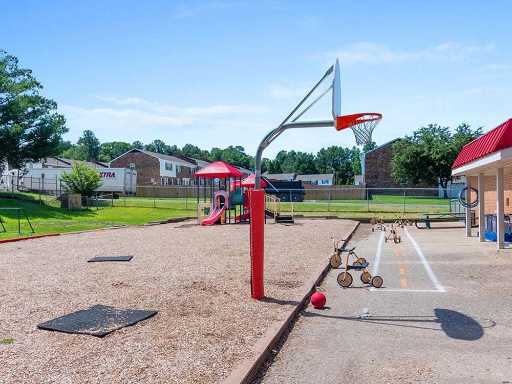 Basketball hoop on a playground with red ball and tricycles