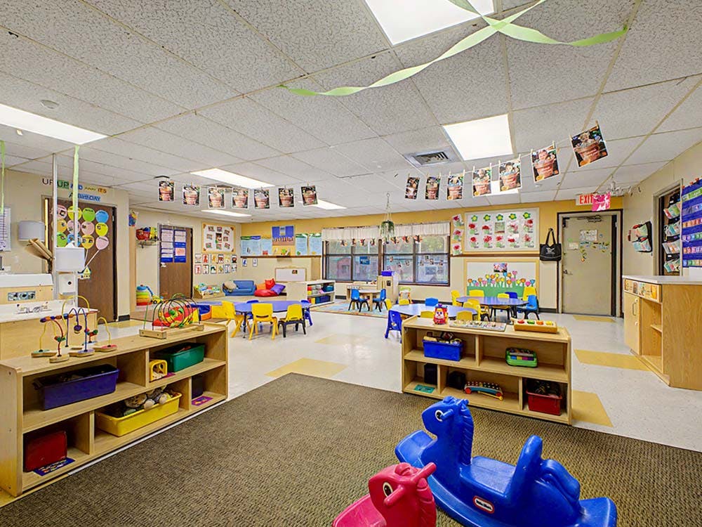 Colorful playroom with small tables and chairs, shelves, and rocking toys