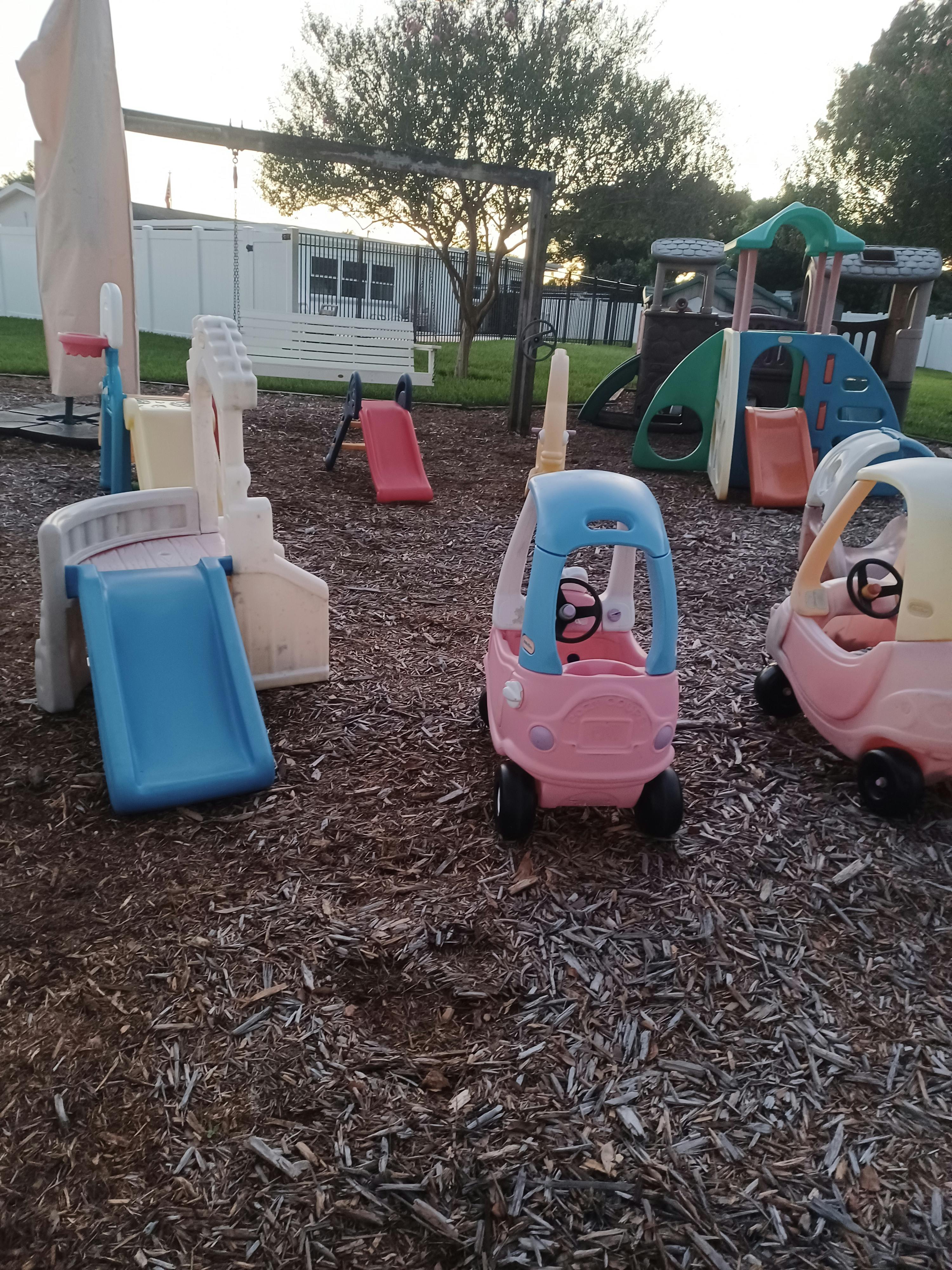 Playground with slides, swings, and toy cars on wood chips