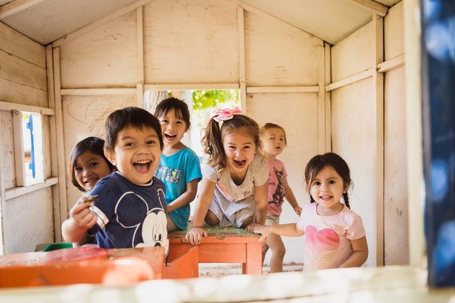 Group of children playing inside a small wooden structure