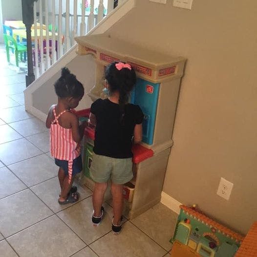 Two children playing with a toy kitchen set