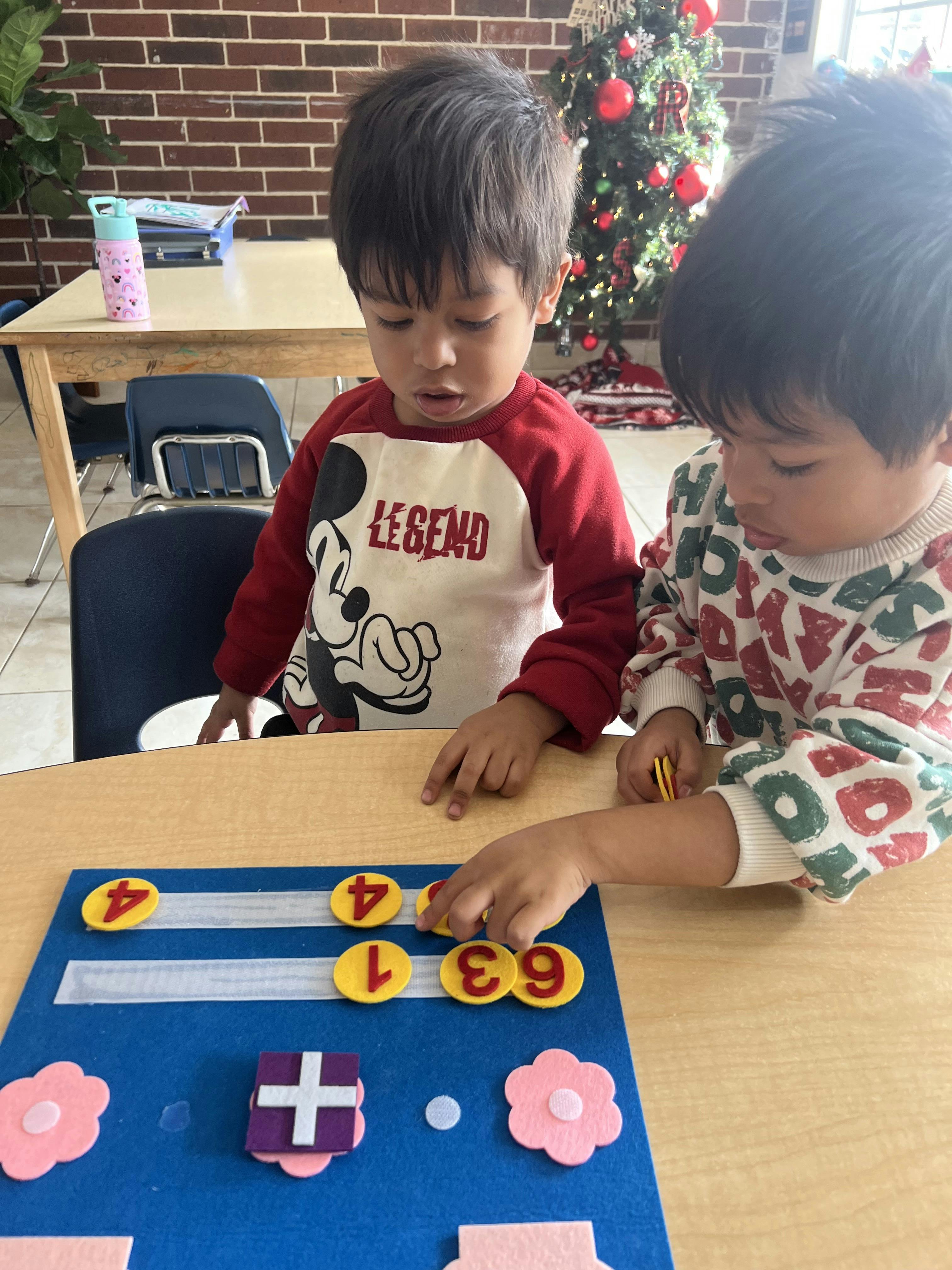 Two children playing with number tiles on a blue felt board