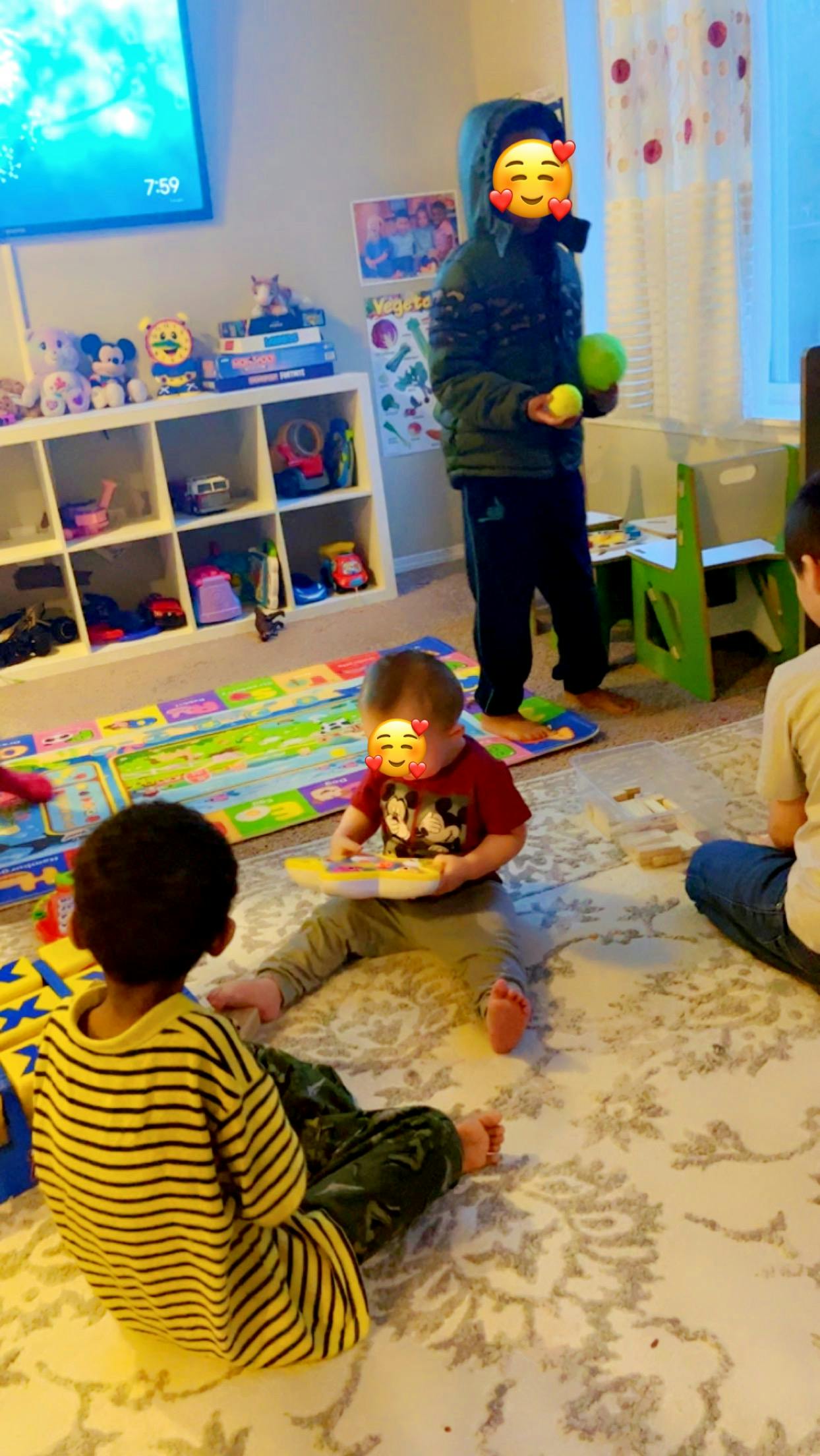 Three children playing on a rug in a room with toys