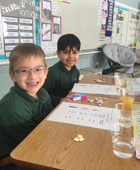 Two children sitting at desks in a classroom