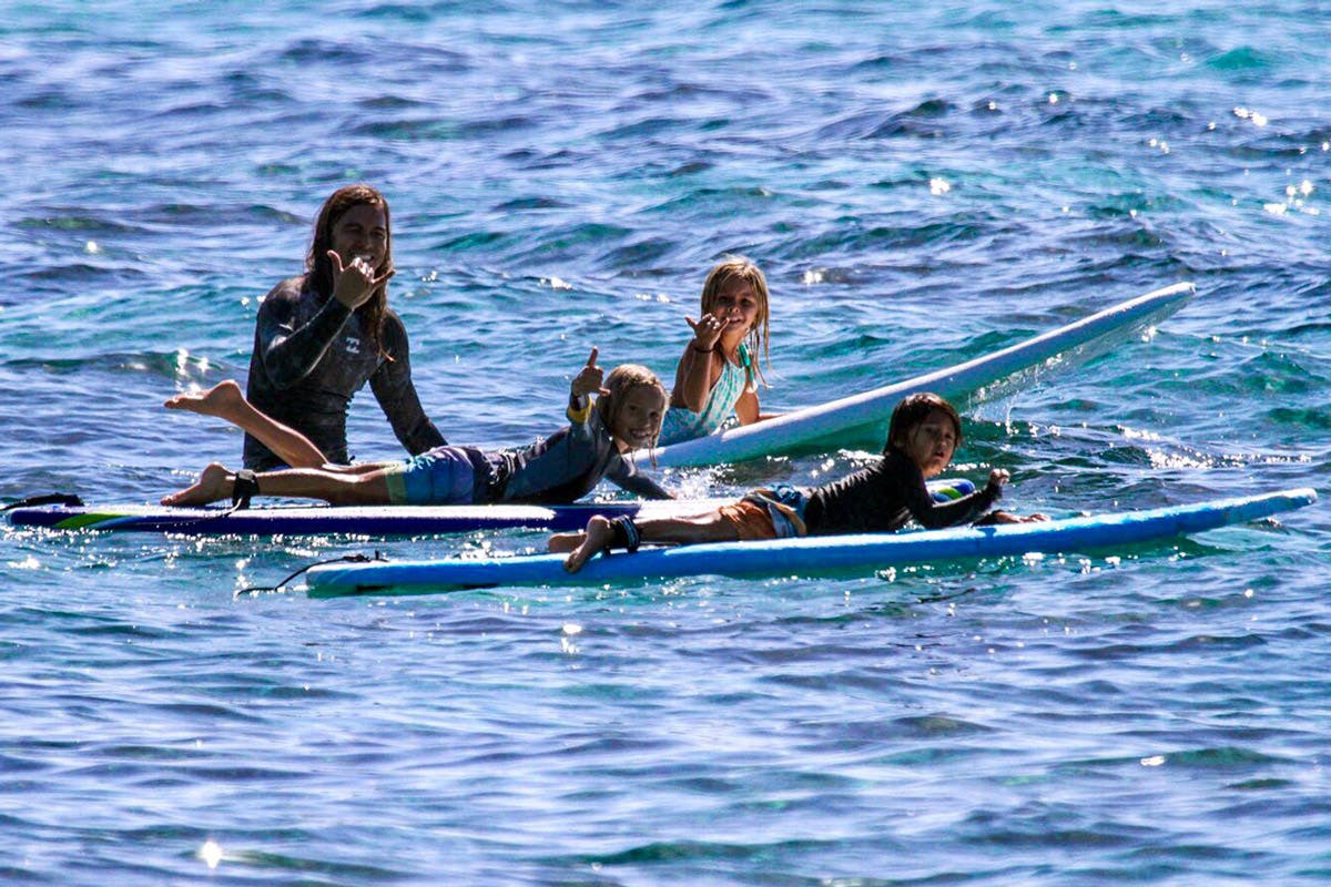 Person and two children on surfboards in the water