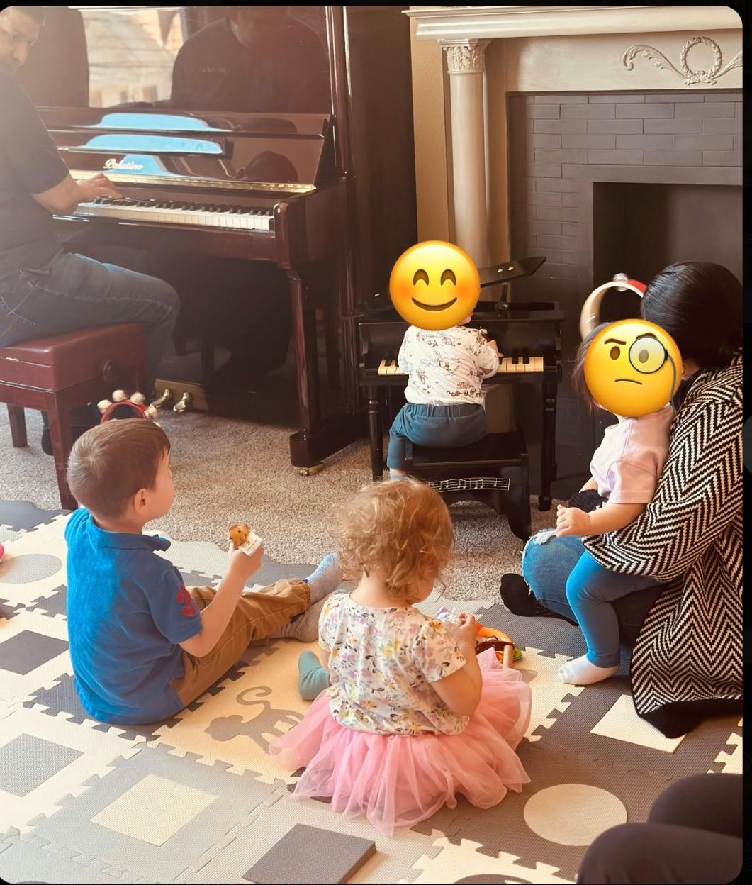 Group of children and an adult gathered around pianos in a room