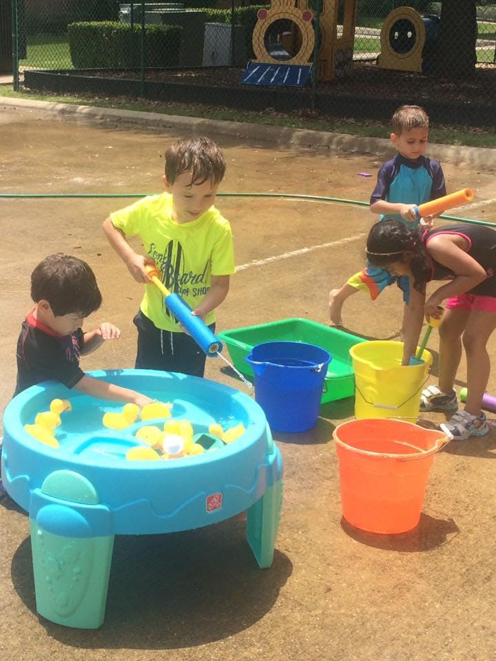 Children playing with water toys and buckets outdoors