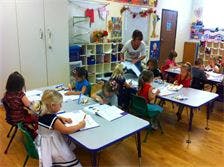 Adult and children at tables in a classroom