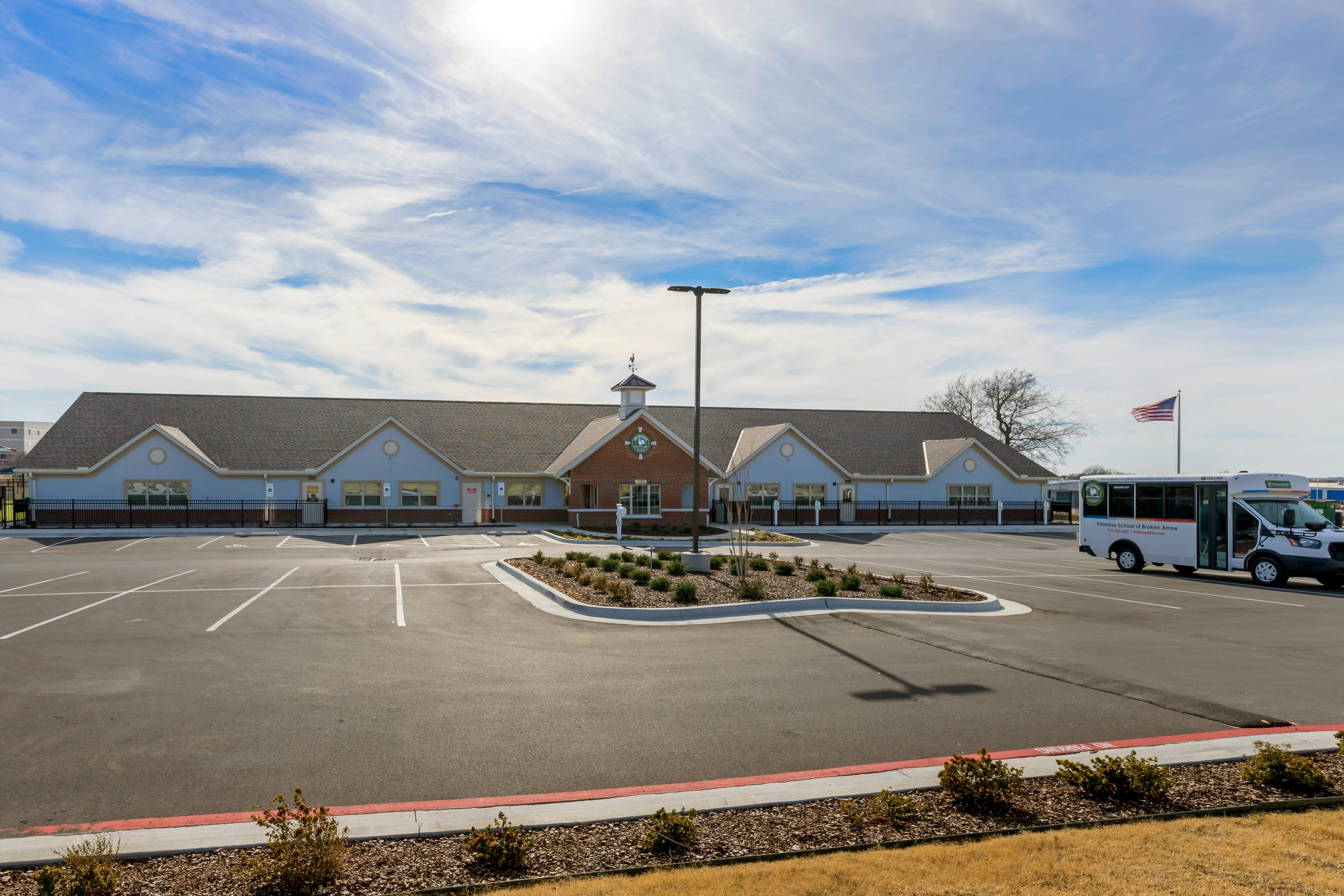 A school building with a parking lot and a white shuttle bus