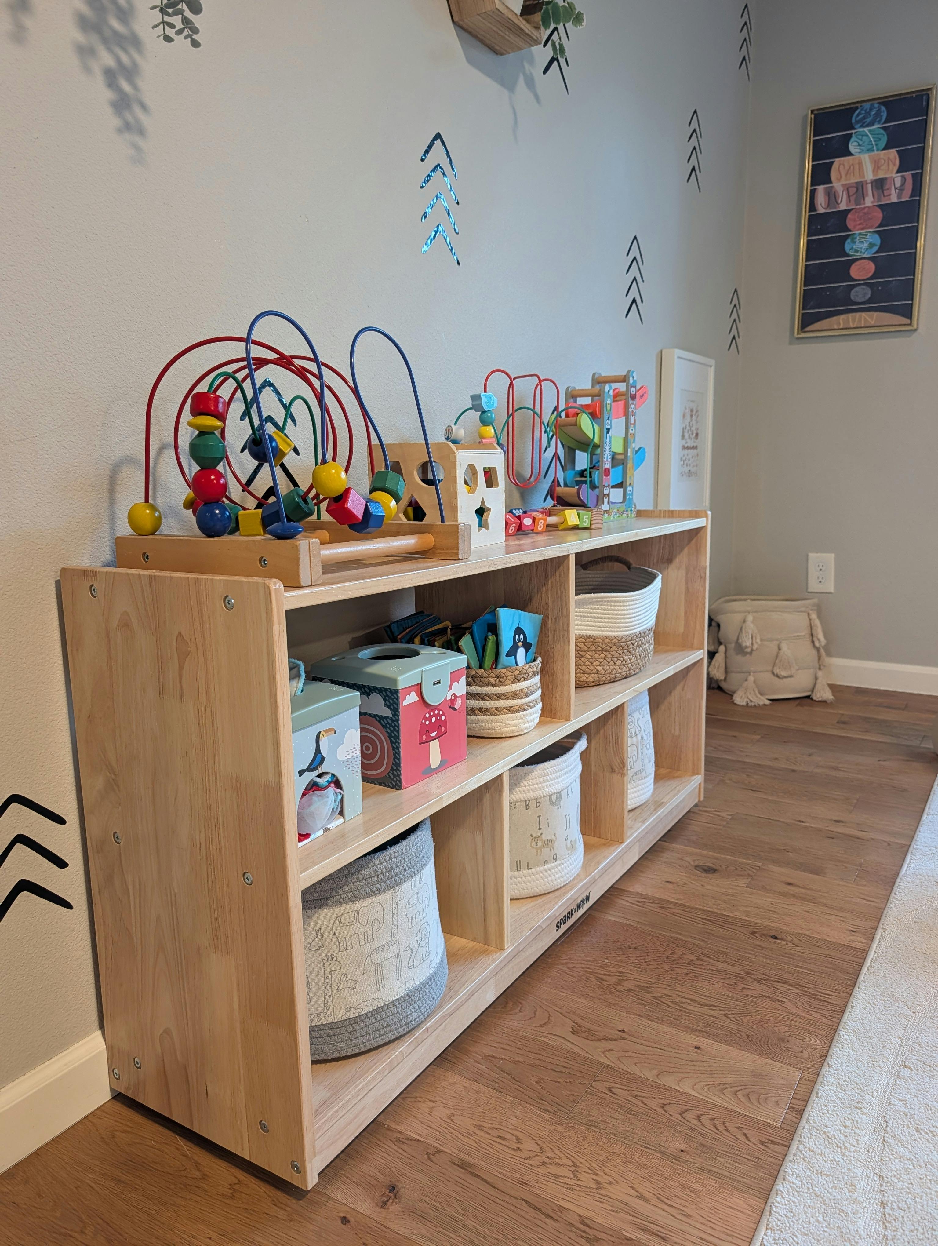 Wooden shelving unit for children filled with toys and storage baskets