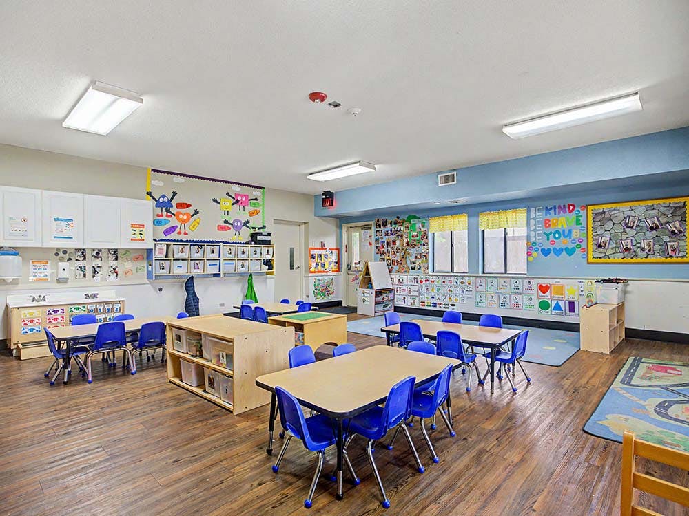 Empty classroom with small tables, blue chairs, and colorful decorations