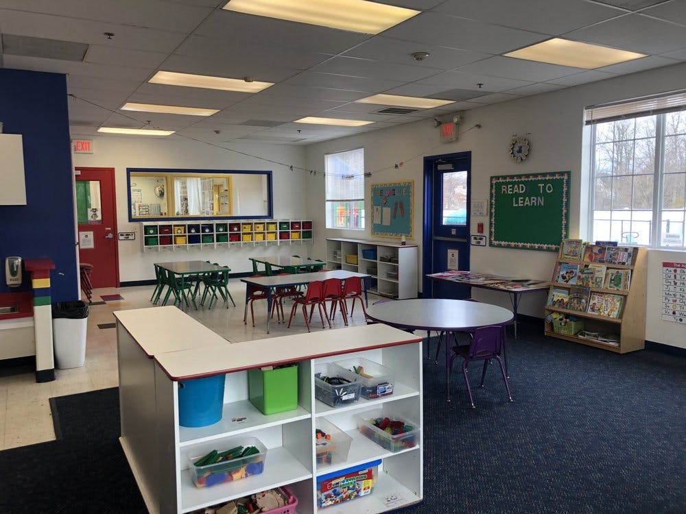 Classroom with small tables and chairs, storage shelves, and a green board that says "Read to Learn"