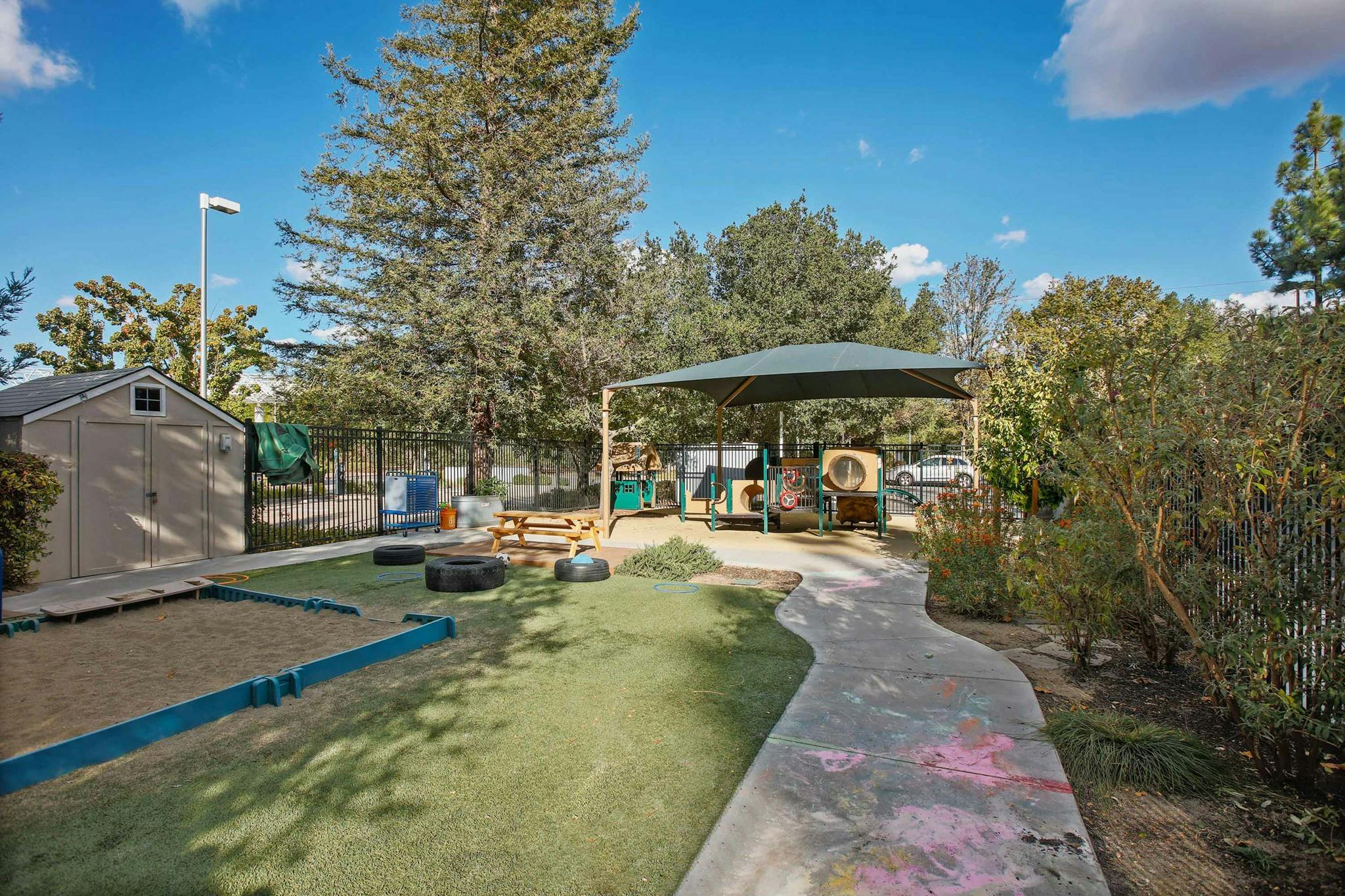 Outdoor playground with sandpit, shed, and covered play area
