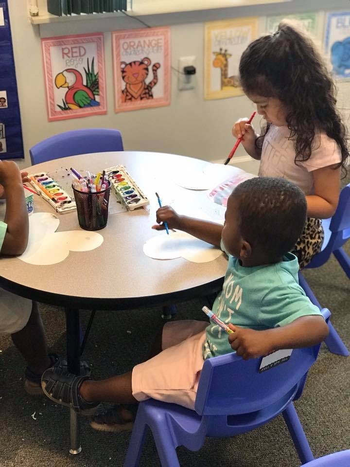 Children painting at a table in a classroom