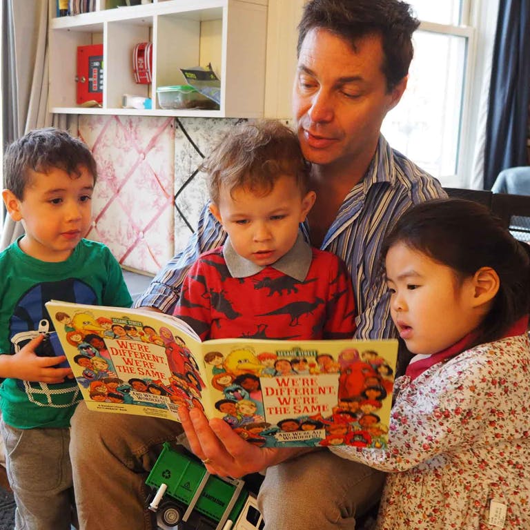 Adult reading a book to three children