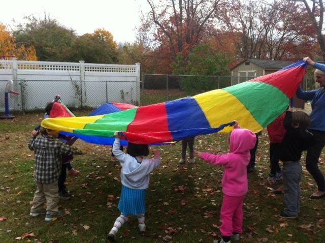 Children playing with a colorful parachute outdoors