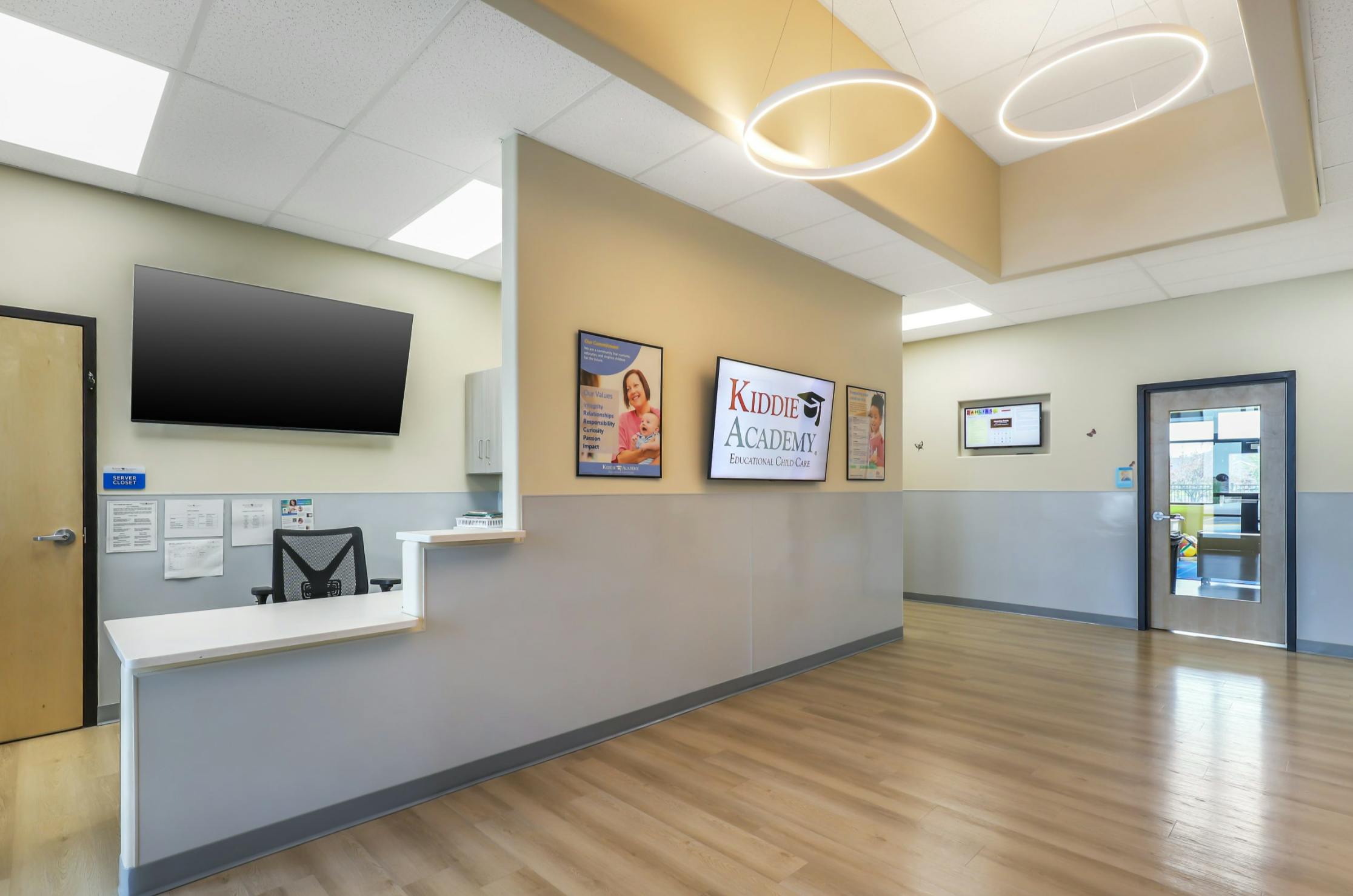 Reception desk with a monitor and a TV screen displaying "Kumon Academy"