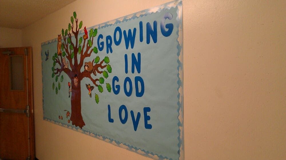 Bulletin board with tree and text "Growing in God Love"