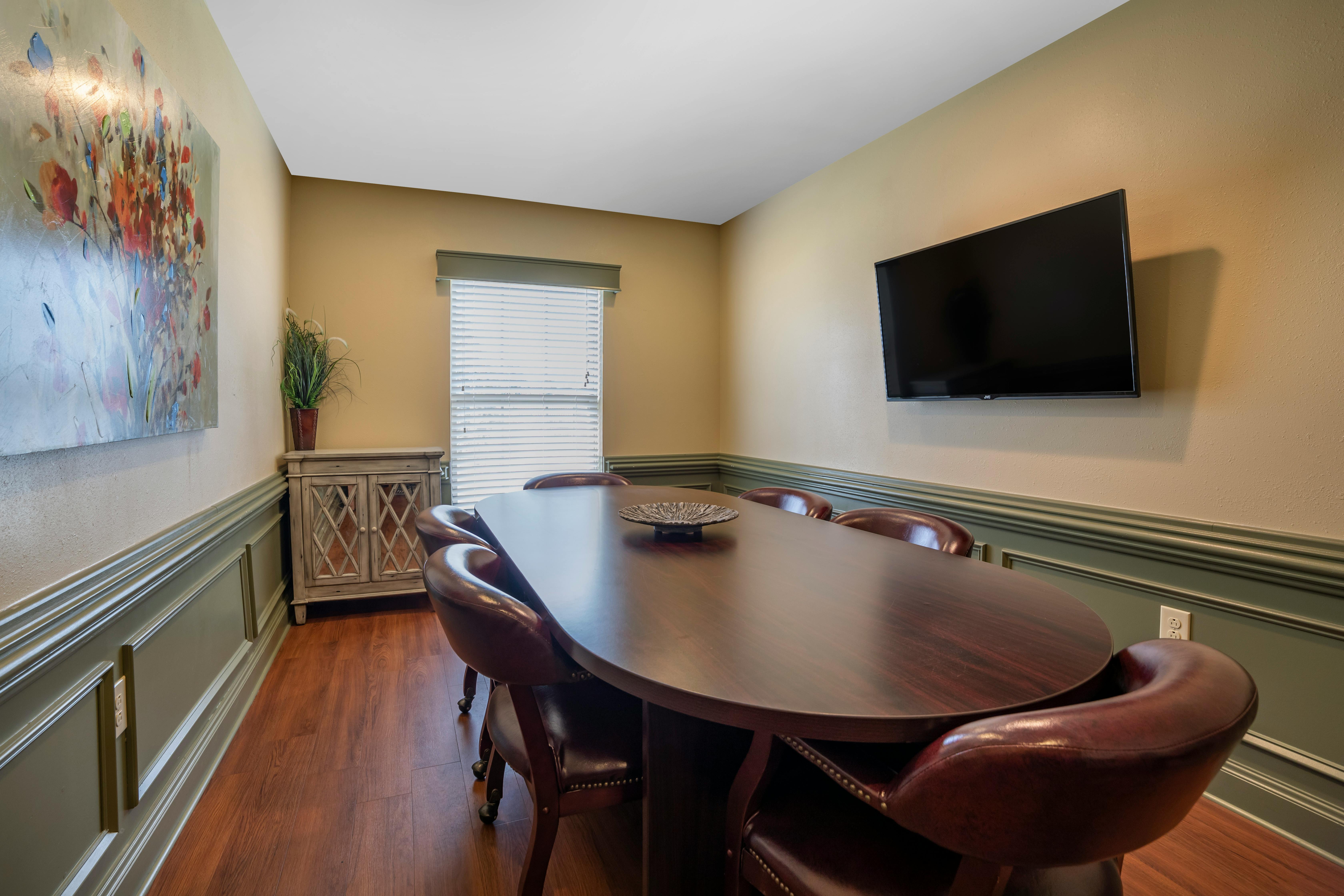 oval wooden table surrounded by brown leather chairs