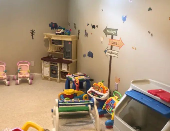 Playroom with toy kitchen, baby chairs, and various colorful toys