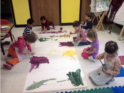 Children painting on a large sheet of paper on the floor