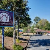 Sign for "Learning Kids School" next to a parking lot and building