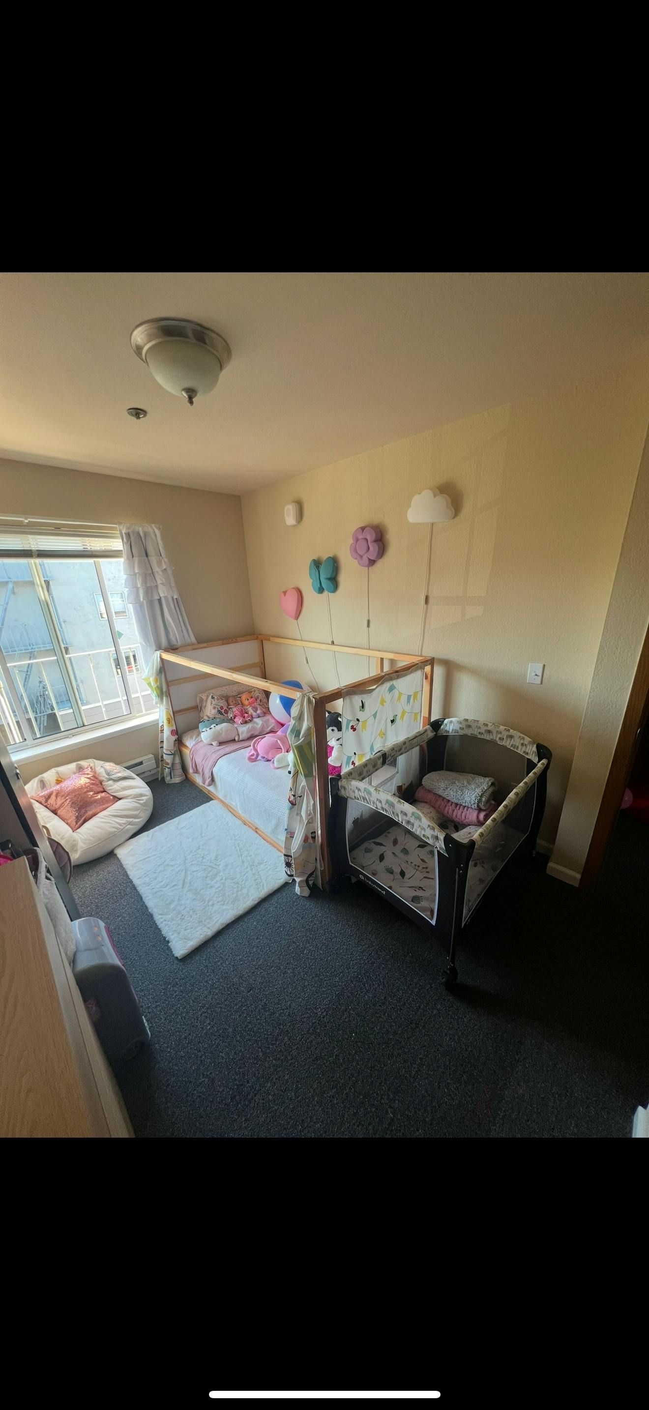 Children bedroom with a house-frame floor bed, playpen, and beanbag chair