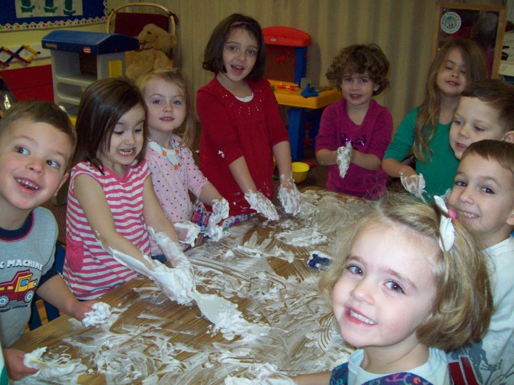 Group of children playing with white foam on a table