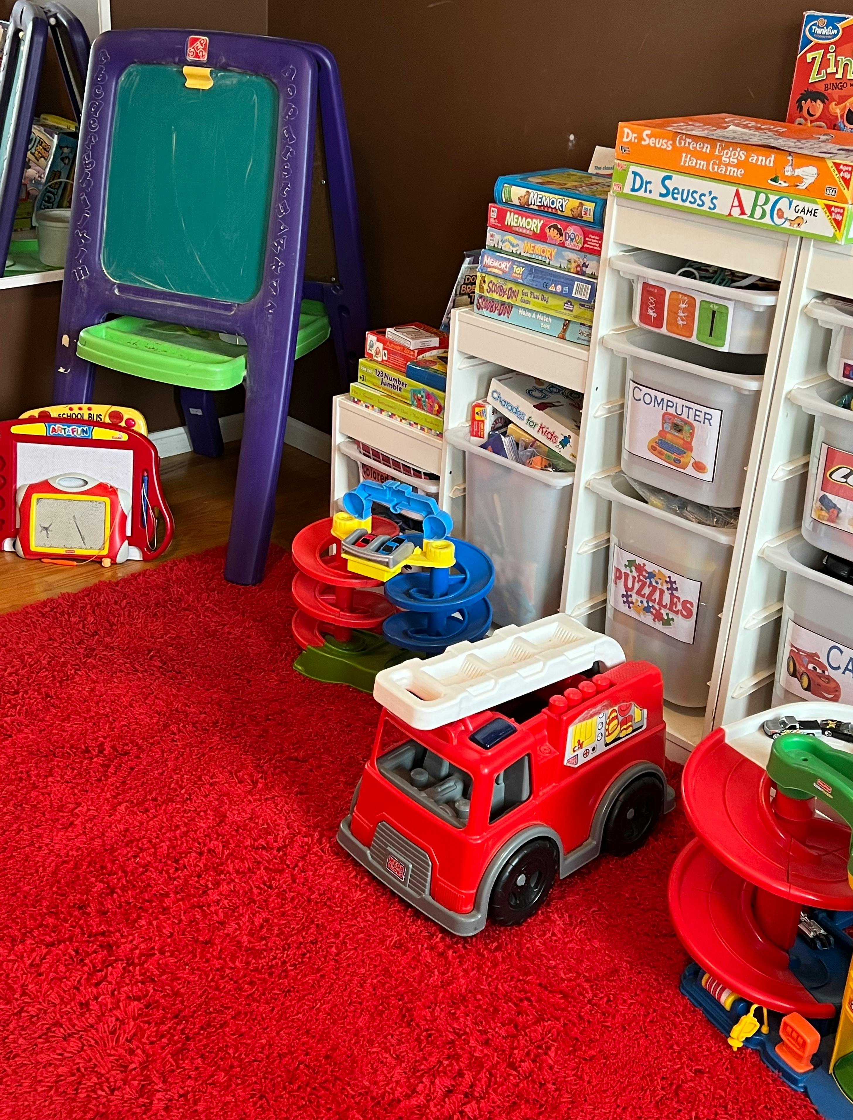 Children's toys including an easel, fire truck, and storage shelves