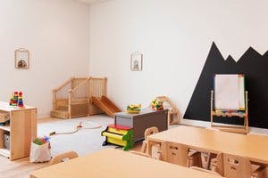 Children's play area with wooden slide, tables, and mountain mural