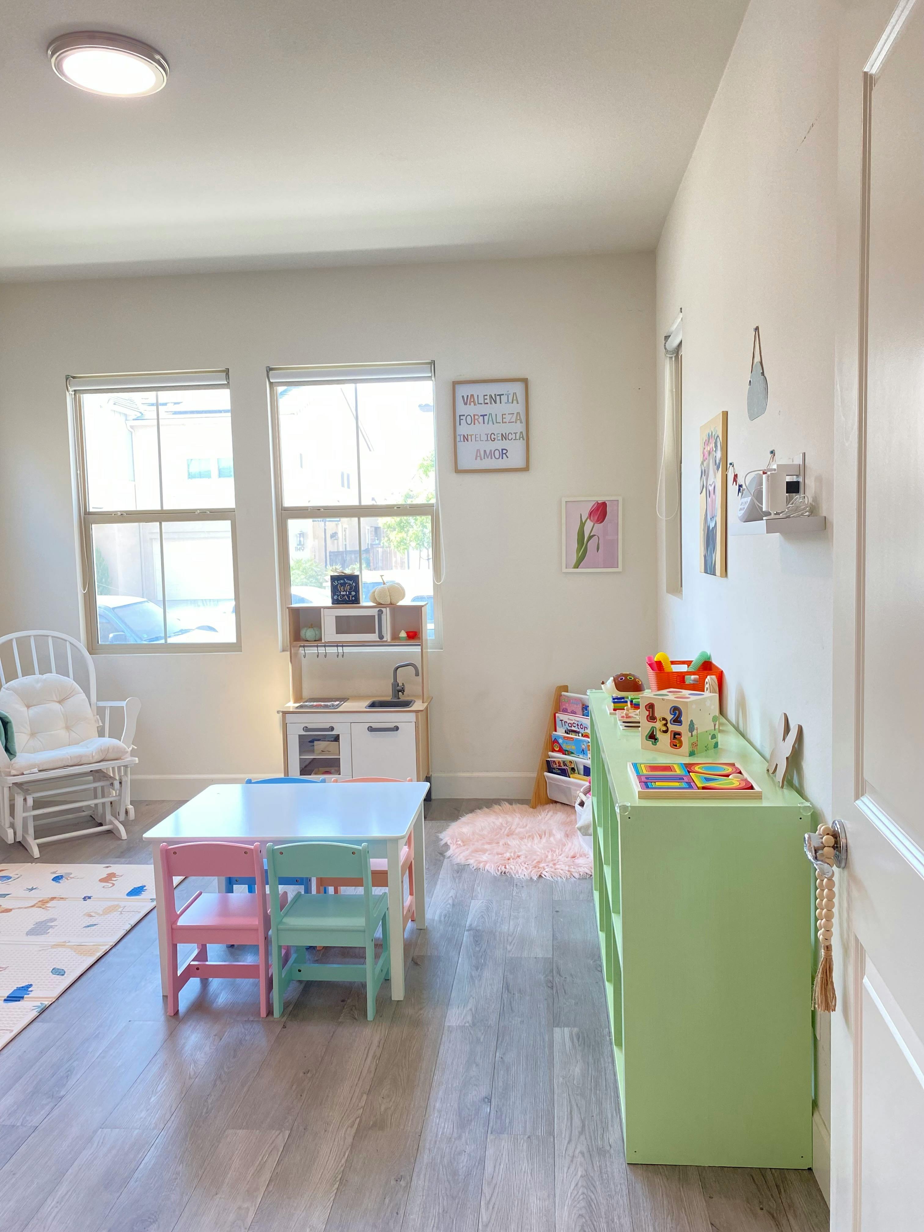 Playroom with small table and chairs, toy kitchen, and green storage unit