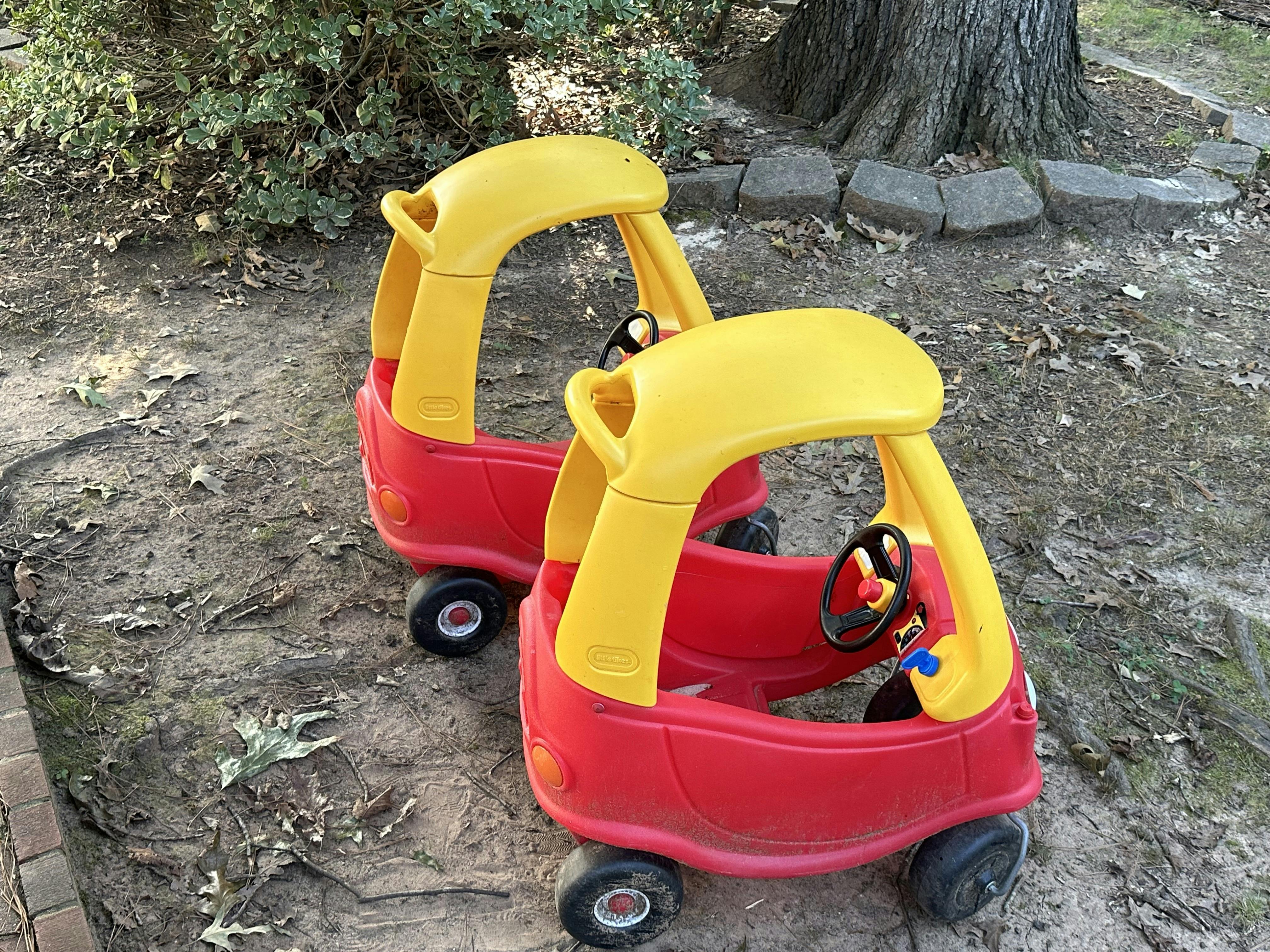 Two red and yellow toy cars outdoors