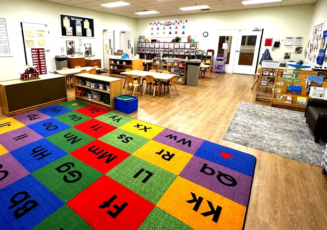 Colorful alphabet rug in a preschool classroom with small tables and chairs