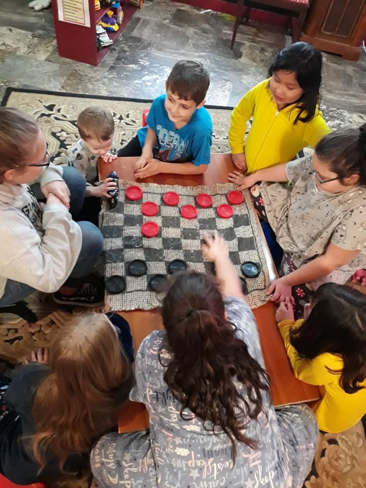 Group of children and adults playing checkers