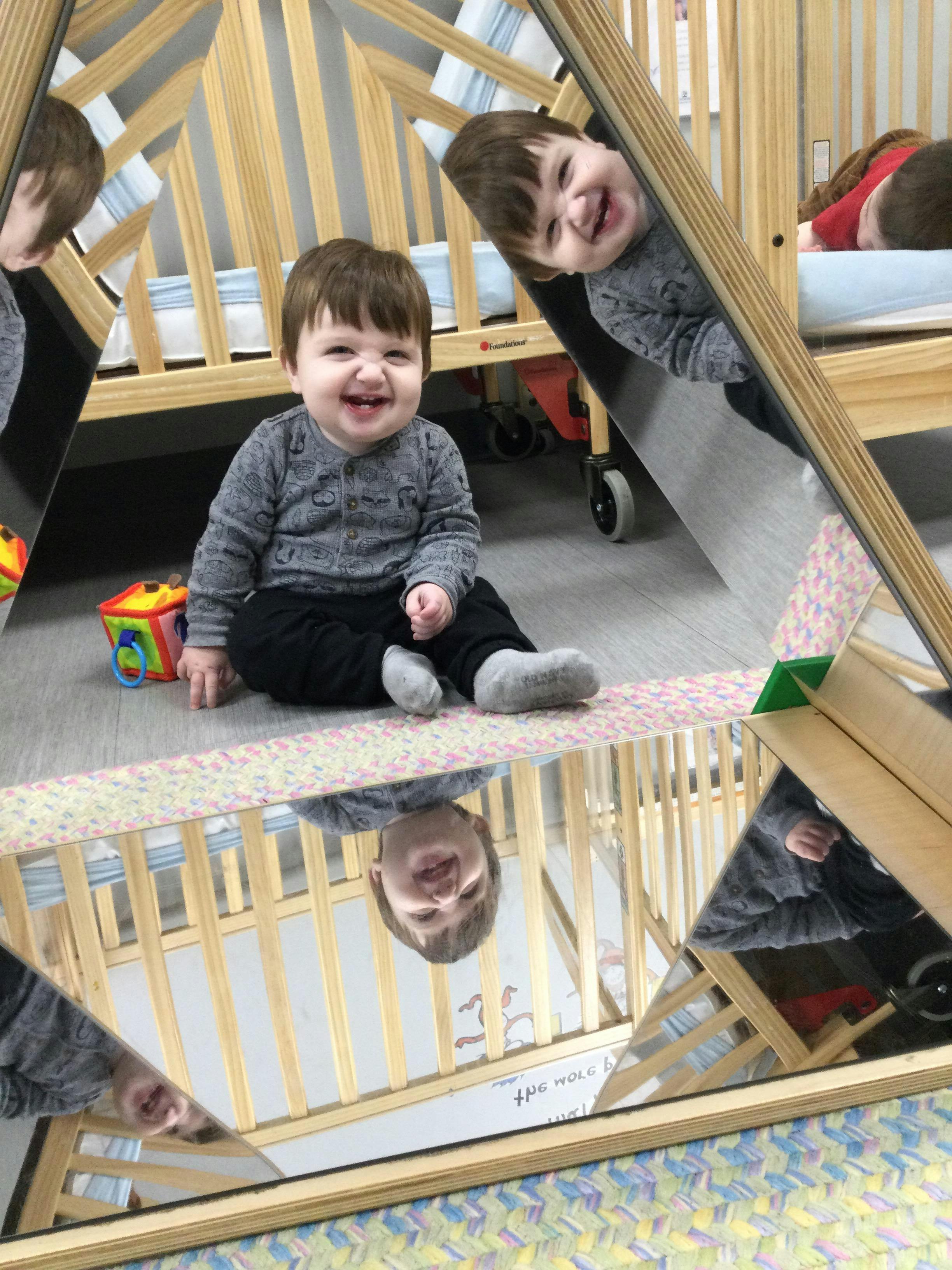 Child sitting on floor with reflections in mirrors